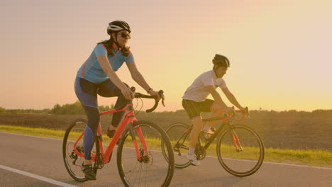 Empty-Space.-Sporty-friends-on-bicycle-on-sunset.-Couple-cyclist-go-along-coast.-Sport-in-Nature-background.-Group-of-people-two-road-biker-in-sunset.